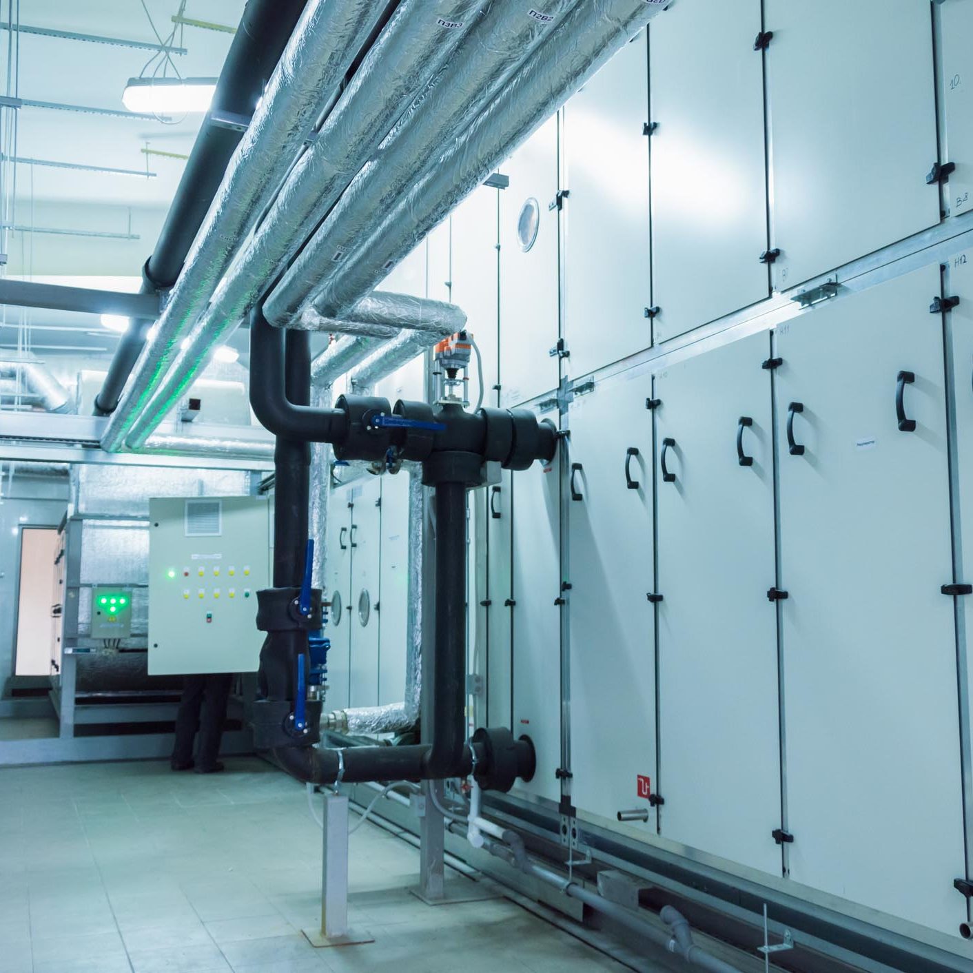 Side view of the huge gray industrial air handling unit in the ventilation plant room