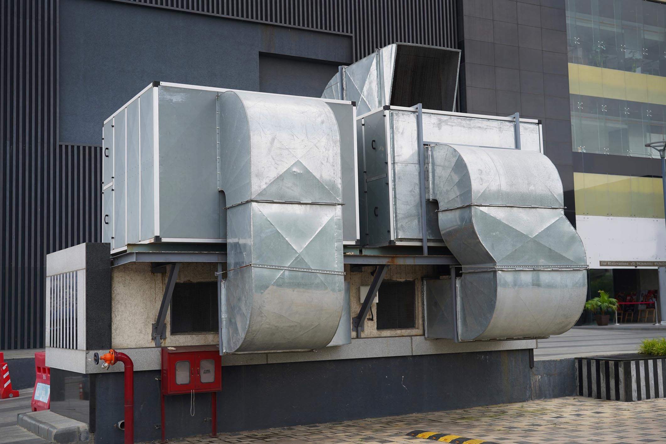 Industrial HVAC Air Duct System and Ventilation Units Installed Outside Commercial Building. Large HVAC system with galvanized air ducts and ventilation units installed on the exterior of a commercial building. Industrial heating, ventilation, and air conditioning equipment used for air circulation, temperature control, and maintaining indoor air quality in malls, offices, and large complexes